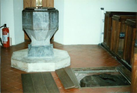 A pagan standing stone in the floor by a Christian font